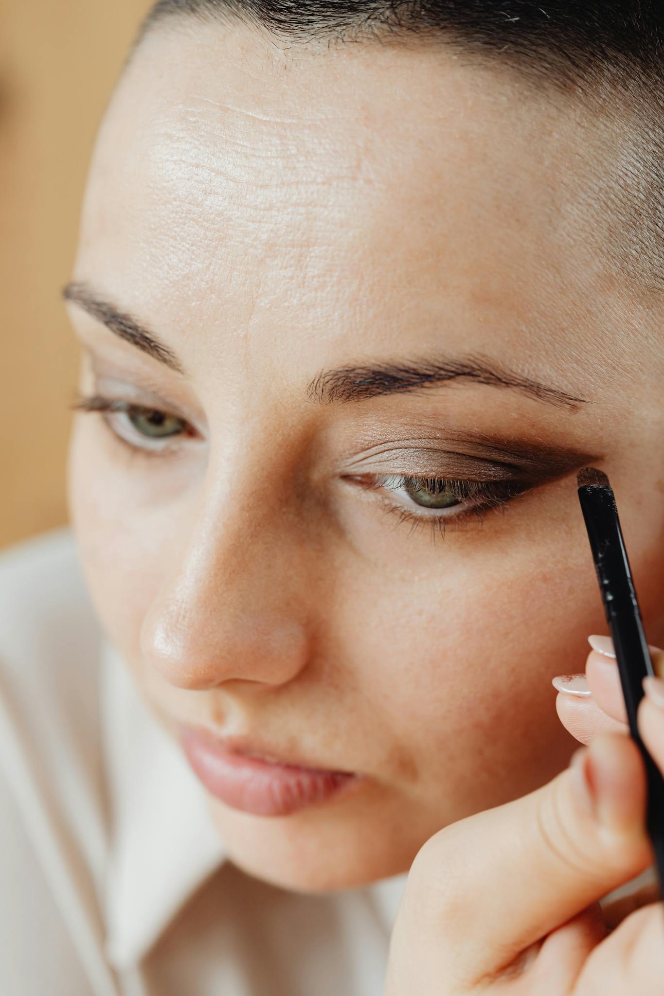 Detailed close-up shot of a woman applying eyeshadow with a makeup brush for a beauty routine.